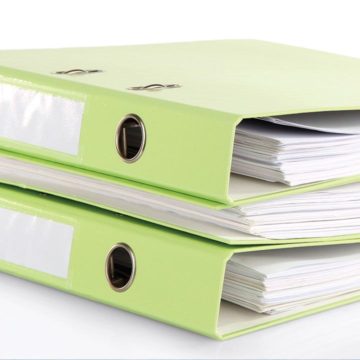 Two light green lever arch files stacked on top of each other, full of papers, on a white background