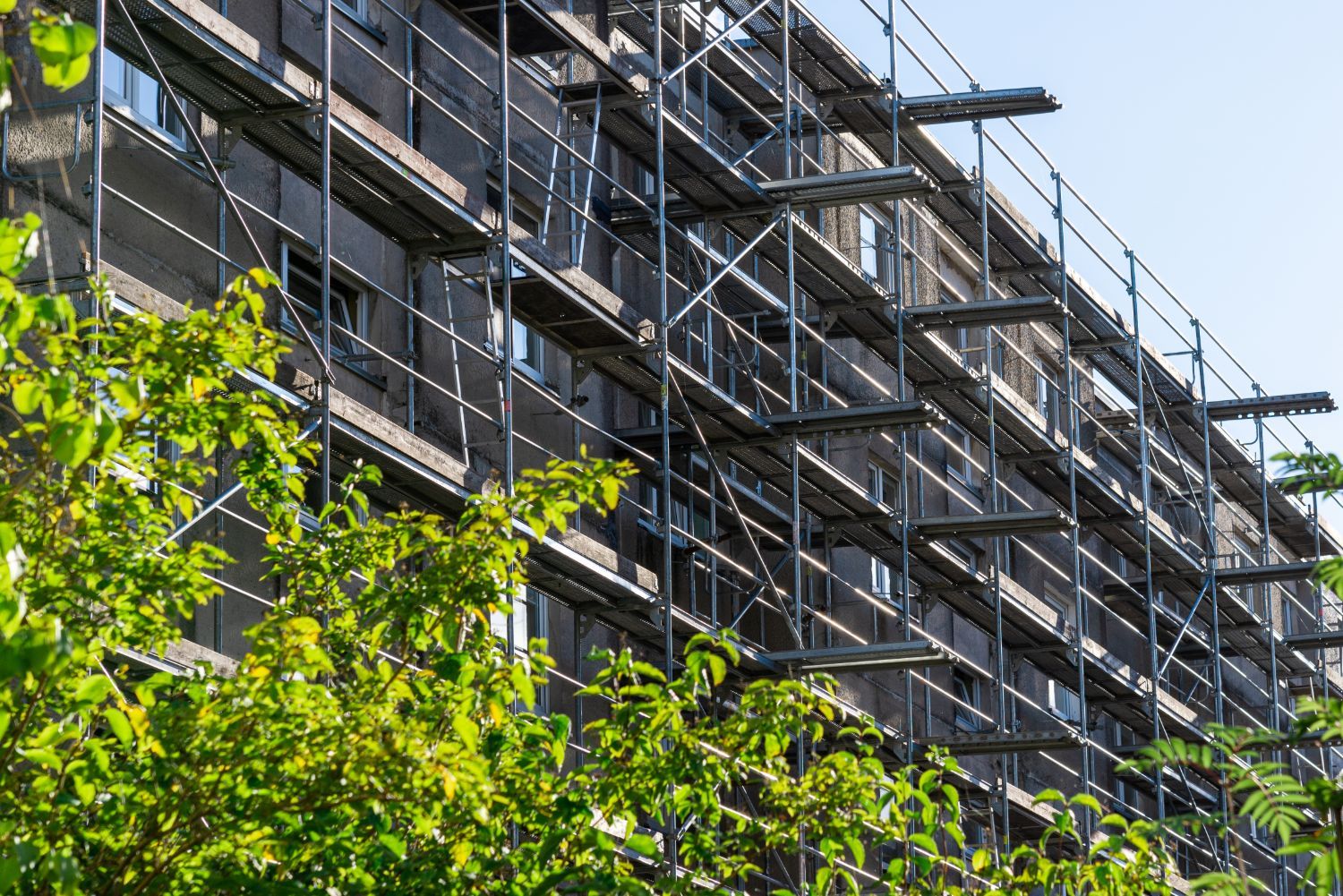 Állványzattal körbevett, felújítás alatt álló többemeletes lakóépület homlokzata